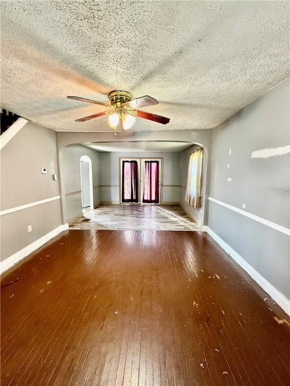 210 Griscom St, Dawson, PA 15428 - empty room with arched walkways, hardwood / wood-style floors, ceiling fan, baseboards, and a textured ceiling