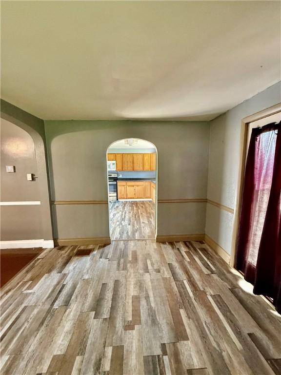 210 Griscom St, Dawson, PA 15428 - spare room featuring arched walkways, light wood-type flooring, and baseboards