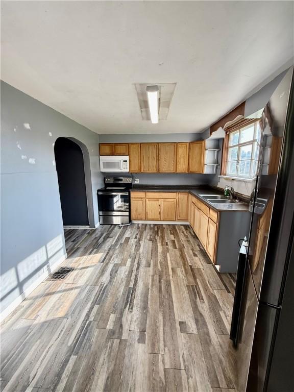 210 Griscom St, Dawson, PA 15428 - kitchen featuring stainless steel electric stove, white microwave, a sink, wood finished floors, and arched walkways