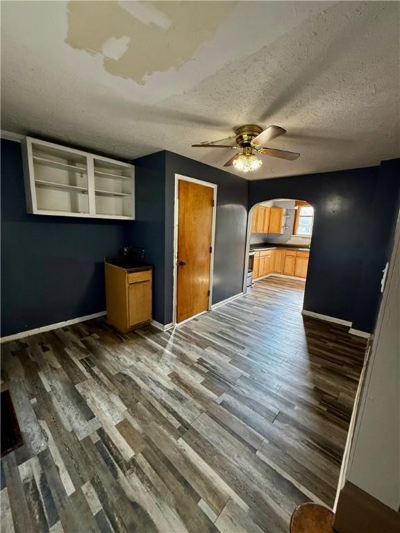 210 Griscom St, Dawson, PA 15428 - unfurnished living room featuring arched walkways, wood finished floors, ceiling fan, a textured ceiling, and baseboards