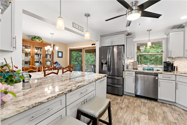 315 Yarrow Ln, Pleasant Hills, PA 15236 - kitchen with appliances with stainless steel finishes, backsplash, a ceiling fan, a breakfast bar area, and light wood finished floors
