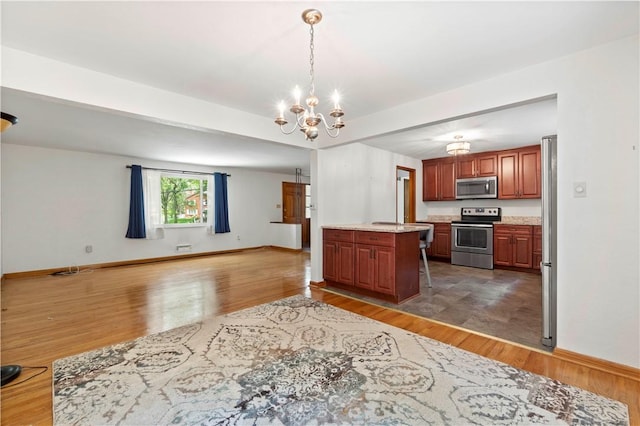 455 Darrell Dr, Penn Hills, PA 15235 - kitchen featuring appliances with stainless steel finishes, open floor plan, light countertops, wood finished floors, and a chandelier