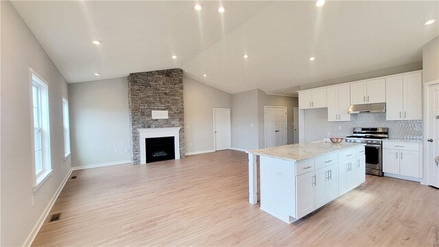 168 Twin Oaks Dr, Buffalo Twp, PA 16055 - kitchen featuring stainless steel gas stove, under cabinet range hood, vaulted ceiling, white cabinets, and light wood-style floors