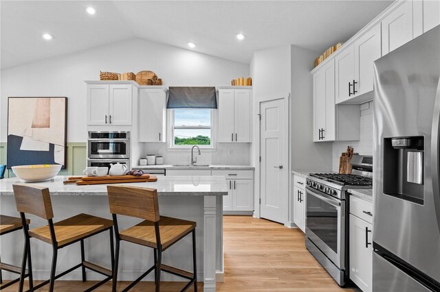 168 Twin Oaks Dr, Buffalo Twp, PA 16055 - kitchen with appliances with stainless steel finishes, a breakfast bar area, tasteful backsplash, white cabinetry, and lofted ceiling