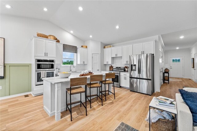 168 Twin Oaks Dr, Buffalo Twp, PA 16055 - kitchen with stainless steel appliances, white cabinetry, a center island, a breakfast bar, and vaulted ceiling