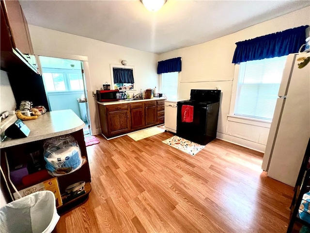 127 Tipple Row Rd, Hempfield Twp Wml, PA 15601 - kitchen with black range with electric stovetop, freestanding refrigerator, light wood-type flooring, and light countertops