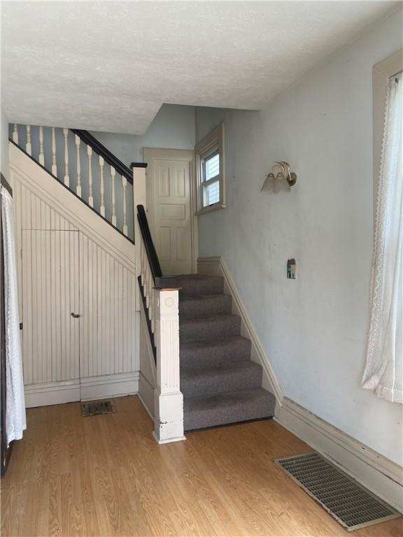 622 E 10th Ave, Tarentum, PA 15084 - staircase featuring wood finished floors, baseboards, and a textured ceiling