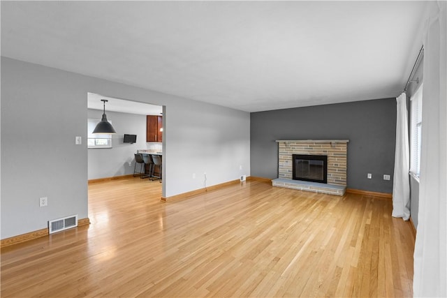 127 Craig Dr, Hempfield Twp Wml, PA 15601 - unfurnished living room with light wood finished floors, a brick fireplace, and baseboards