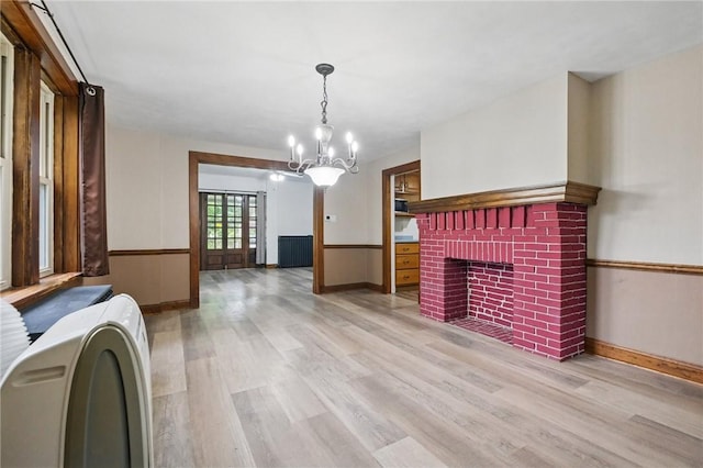 3855 Hiawatha St, Brighton Heights, PA 15212 - unfurnished living room with light wood finished floors, a brick fireplace, a chandelier, washer / dryer, and wainscoting