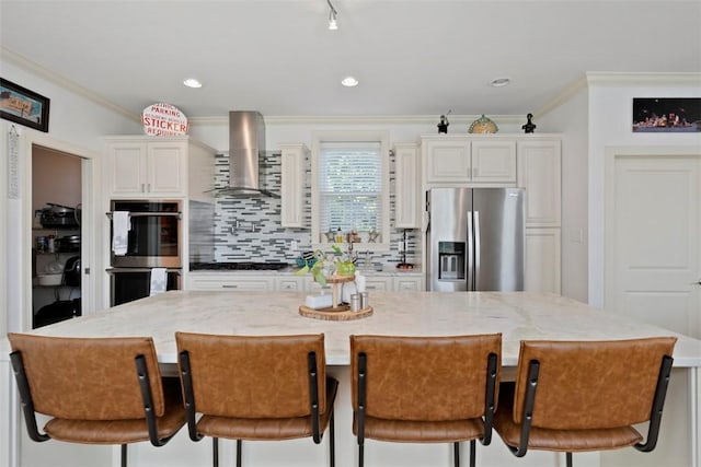 2700 Sumner St, South Side, PA 15203 - kitchen featuring appliances with stainless steel finishes, wall chimney exhaust hood, crown molding, decorative backsplash, and light stone counters