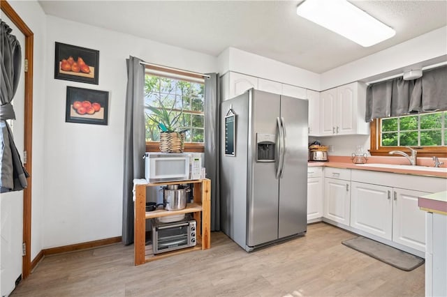 104 Overholt Dr, Scottdale, PA 15683 - kitchen with stainless steel fridge, white microwave, a sink, light wood finished floors, and white cabinetry