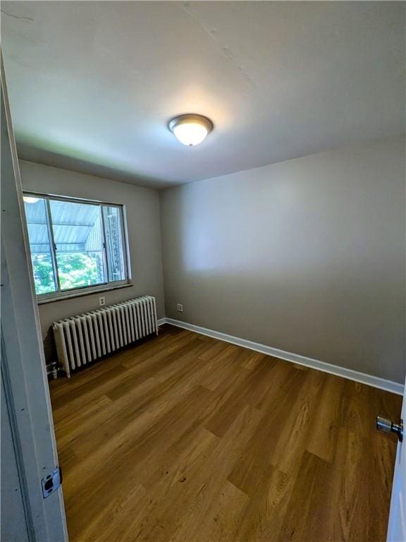 518 Glenn St, Wilmerding, PA 15148 - empty room with radiator heating unit, wood finished floors, and baseboards