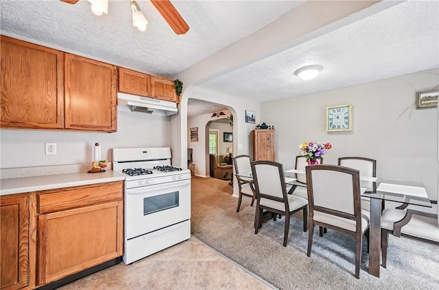283 S 5th St, Sharpsville, PA 16150 - kitchen featuring white gas stove, under cabinet range hood, arched walkways, a textured ceiling, and brown cabinets