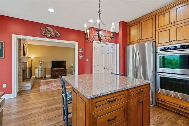 112 Beaver Creek Ct, Sewickley, PA 15143 - kitchen with appliances with stainless steel finishes, a chandelier, light wood finished floors, light stone counters, and brown cabinets