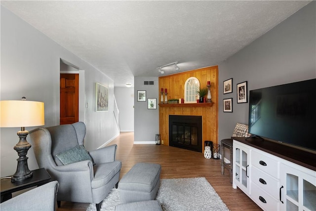2609 Fox Chase Ct, South Fayette, PA 15017 - living area with dark wood-style floors, a glass covered fireplace, a textured ceiling, baseboards, and track lighting