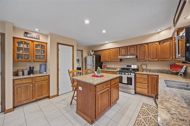 1408 Fernledge Dr, Shaler, PA 15101 - kitchen with stainless steel appliances, under cabinet range hood, brown cabinets, a kitchen island, and light stone counters