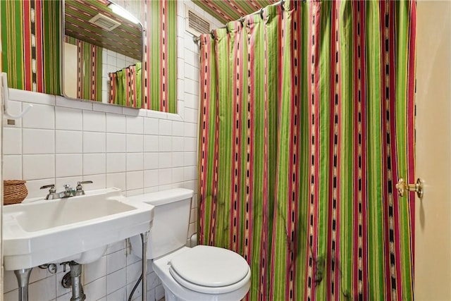 5048 5th Ave Unit 101, Shadyside, PA 15232 - bathroom featuring tile walls, toilet, a shower with shower curtain, a sink, and decorative backsplash