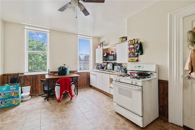 1332 Diana St, Troy Hill, PA 15212 - kitchen featuring gas range gas stove, wainscoting, plenty of natural light, a ceiling fan, and white cabinetry