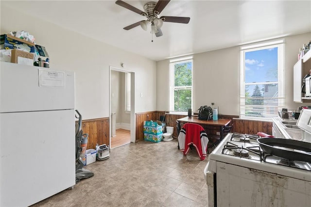 1332 Diana St, Troy Hill, PA 15212 - kitchen with white appliances, wainscoting, wooden walls, ceiling fan, and light tile patterned floors