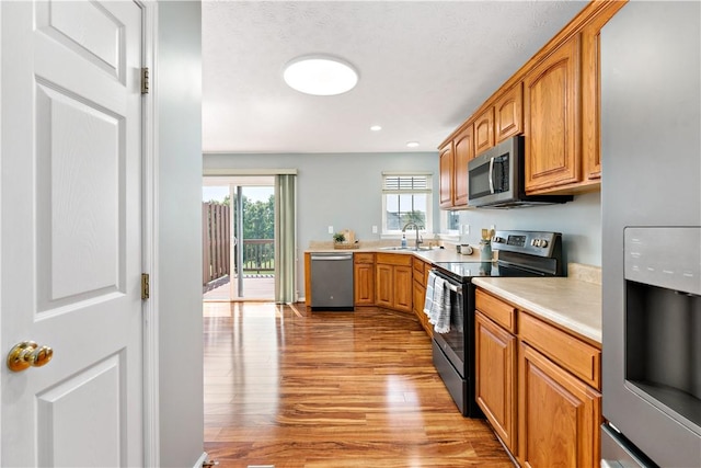 2000 Michael Dr, Baldwin Boro, PA 15227 - kitchen with stainless steel appliances, light wood-style flooring, a sink, light countertops, and brown cabinetry