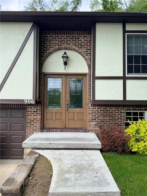906 Arch Ave, Castle Shannon, PA 15234 - view of exterior entry with stucco siding, brick siding, and a garage