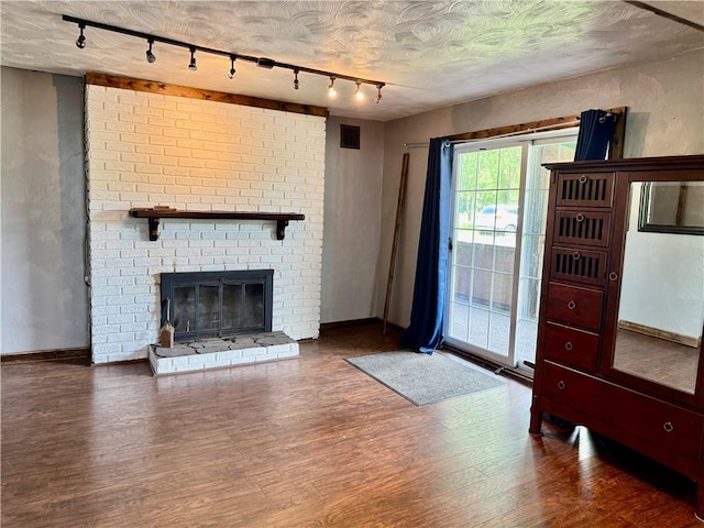 128 Main St, Perry Twp Fay, PA 15473 - unfurnished living room featuring rail lighting, wood finished floors, baseboards, and a brick fireplace