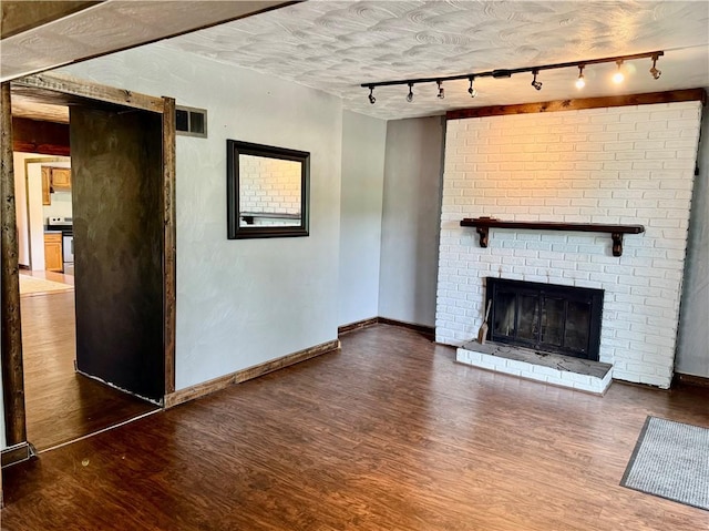 128 Main St, Perry Twp Fay, PA 15473 - unfurnished living room featuring rail lighting, wood finished floors, a fireplace, and baseboards