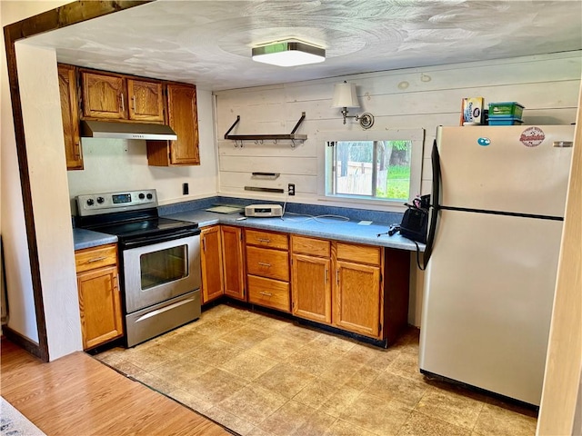 128 Main St, Perry Twp Fay, PA 15473 - kitchen with freestanding refrigerator, electric range, under cabinet range hood, brown cabinetry, and dark countertops