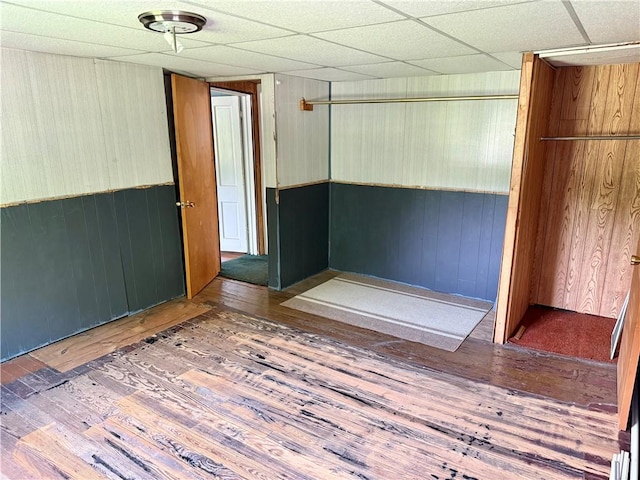 128 Main St, Perry Twp Fay, PA 15473 - empty room featuring hardwood / wood-style floors, wooden walls, and a drop ceiling