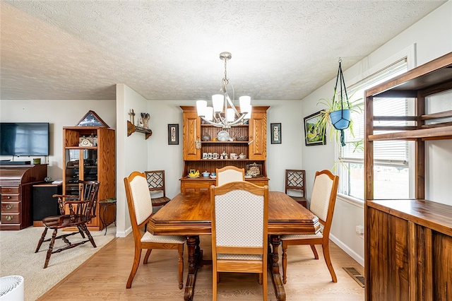 204 Fosterville Rd, Hempfield Twp Wml, PA 15601 - dining space with a chandelier, light wood-style floors, a textured ceiling, and baseboards