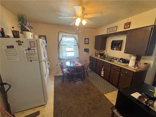 423 Lowell St, Vandergrift Wml, PA 15690 - kitchen with freestanding refrigerator, dark brown cabinets, ceiling fan, a textured ceiling, and light countertops
