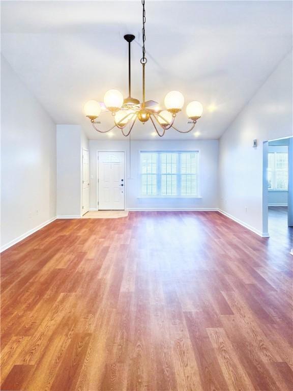 121 Columbus Dr, Punxsutawney Area School District, PA 15767 - unfurnished living room featuring a chandelier, vaulted ceiling, wood finished floors, and baseboards