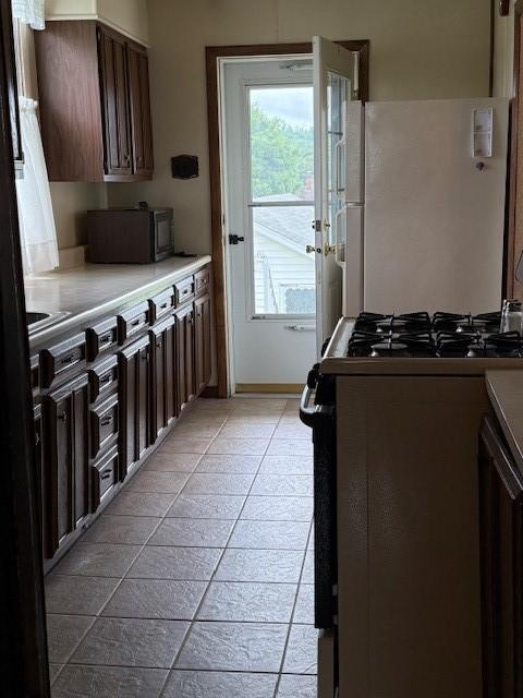 134 E Harvey Ave, Masontown, PA 15461 - kitchen with gas range oven, light countertops, and light tile patterned flooring
