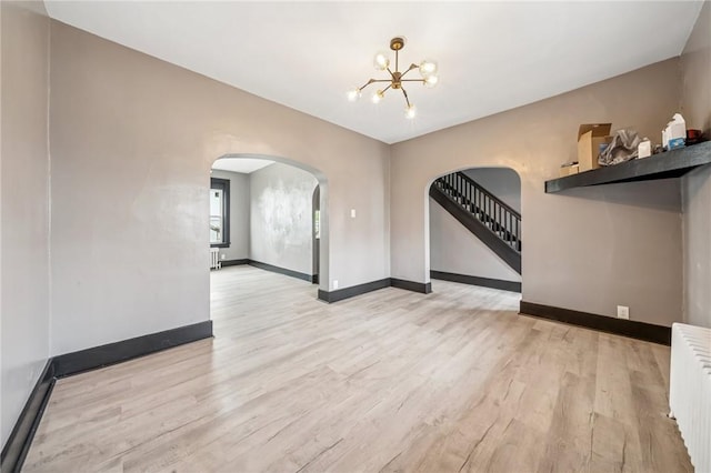 1105 Stieren Ave, Brackenridge, PA 15014 - empty room with arched walkways, radiator heating unit, a chandelier, wood finished floors, and baseboards
