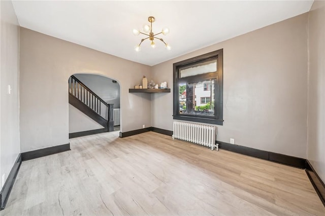 1105 Stieren Ave, Brackenridge, PA 15014 - empty room featuring radiator heating unit, arched walkways, a chandelier, and wood finished floors