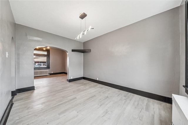 1105 Stieren Ave, Brackenridge, PA 15014 - unfurnished room featuring radiator, arched walkways, light wood-type flooring, and baseboards
