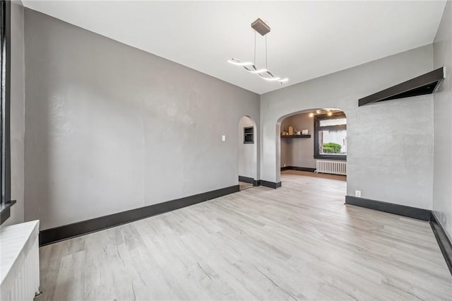 1105 Stieren Ave, Brackenridge, PA 15014 - unfurnished room featuring radiator, arched walkways, light wood-style floors, and baseboards