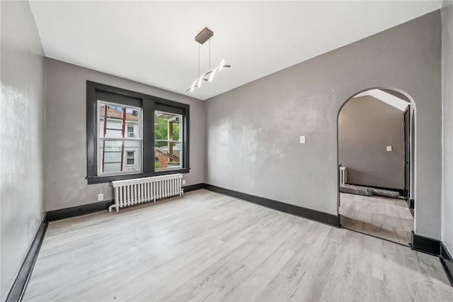 1105 Stieren Ave, Brackenridge, PA 15014 - empty room with radiator heating unit, wood finished floors, baseboards, and arched walkways