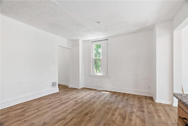 1567 Princeton Blvd, Wilkinsburg, PA 15221 - empty room featuring light wood finished floors, baseboards, and a textured ceiling