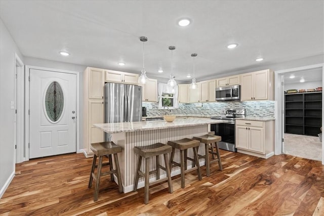259 Old Blackhawk Rd, Chippewa Twp, PA 15010 - kitchen with appliances with stainless steel finishes, wood finished floors, a kitchen island, tasteful backsplash, and a kitchen bar