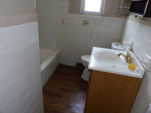 2042 Madison St, Hermitage, PA 16148 - bathroom featuring tile walls, toilet, wood finished floors, vanity, and a bath