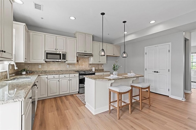 1009 Grey Fox Cir, Scott Twp Sal, PA 15017 - kitchen featuring stainless steel appliances, a sink, light wood-style floors, a center island, and decorative backsplash
