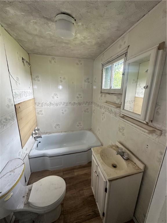 228 Walnut St, Donora, PA 15033 - bathroom featuring vanity, a tub to relax in, and wood finished floors