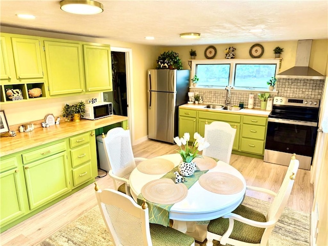 543 N Main St, Masontown, PA 15461 - kitchen featuring green cabinets, appliances with stainless steel finishes, wall chimney range hood, a sink, and light wood finished floors