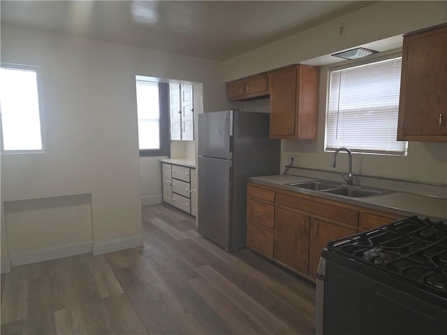 518 Waddell Ave, Clairton, PA 15025 - kitchen featuring a sink, freestanding refrigerator, black range with gas stovetop, light wood-type flooring, and brown cabinetry