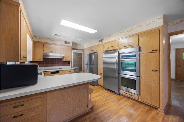 194 Southvue Dr, Whitehall, PA 15236 - kitchen featuring appliances with stainless steel finishes, under cabinet range hood, light countertops, a peninsula, and light wood-style floors