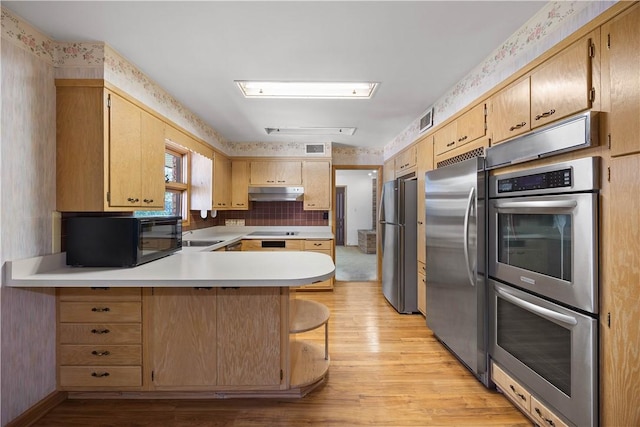 194 Southvue Dr, Whitehall, PA 15236 - kitchen featuring appliances with stainless steel finishes, under cabinet range hood, light wood-type flooring, wallpapered walls, and a peninsula