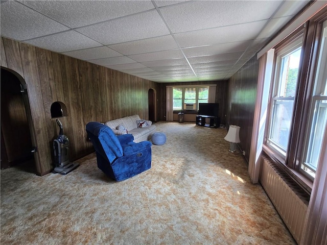 229 Bluff St, Canonsburg, PA 15317 - living area with arched walkways, radiator heating unit, a paneled ceiling, carpet flooring, and wooden walls