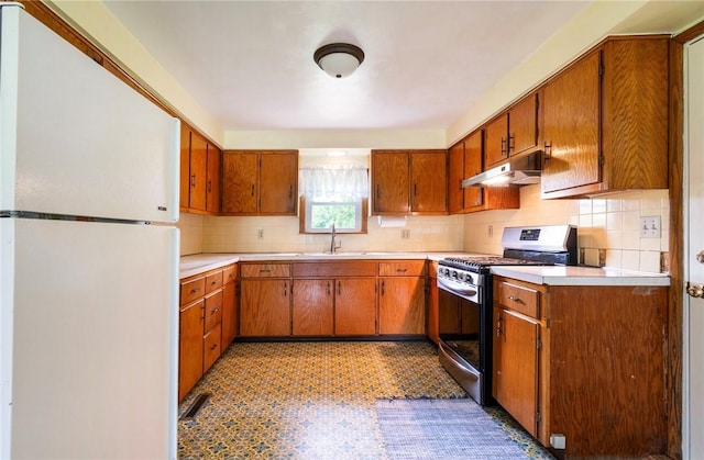 2712 State Route 351, Little Beaver Twp, PA 16120 - kitchen with freestanding refrigerator, gas range, under cabinet range hood, decorative backsplash, and brown cabinets