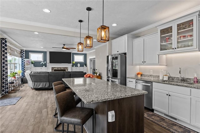 582 Forest Oaks Trl, North Huntingdon, PA 15642 - kitchen featuring stainless steel appliances, a sink, white cabinets, a kitchen island, and a fireplace